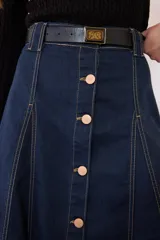 Maxi falda de jean en color azul oscuro, con cierre frontal de botones metálicos y costuras pespunteadas visibles. Tiene diseño evasé que aporta movimiento y caída fluida.