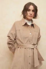 Sobrecamisa de pana color beige, con cuello camisero, cierre frontal con botones metálicos, mangas largas con puños abotonados y lazo ajustable en la cintura.