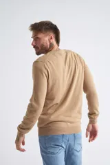 Sweater de tejido de punto color beige, con escote en V, mangas largas y puños y dobladillo acanalados. Presenta un pequeño logo bordado en el pecho.