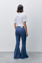 Jean flare de tiro alto, color azul, con calce ajustado en cadera y muslos, y ruedo desflecado.