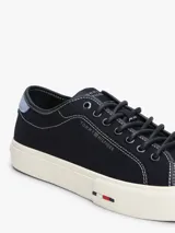 Zapatillas bajas de lona azul marino con costuras blancas contrastantes y suela de goma blanca. Presentan un parche de gamuza celeste en el talón y el logo de Tommy Hilfiger grabado en el lateral.