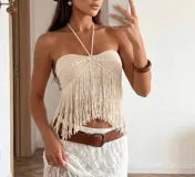 Top de crochet color beige con diseño halter y flecos largos en el ruedo.