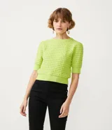 Blusa de punto color verde lima, de manga corta y cuello redondo. Presenta un diseño con textura de relieve en todo el cuerpo y terminaciones acanaladas en cuello, puños y cintura.