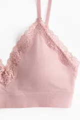 Soutien tipo bralette color rosado, confeccionado en tejido de punto suave, con escote en V adornado con ribete de encaje. Posee breteles finos ajustables y banda inferior elástica.