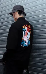 Remera oversize manga corta de algodón de color negro, con diseño holgado en pecho, hombros y mangas, y gran estampa colorida en la espalda.