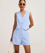 Short sastre de cintura alta con estructura definida, bolsillos laterales decorados con tachuelas metalizadas y recortes delanteros con costura aparente.