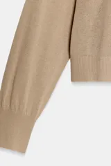 Jersey de punto fino negro con escote en V profundo y manga larga con puños ajustados.
