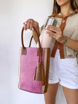 Bolso matero de cuero color fucsia y marrón con textura croco, doble asa de mano marrón y detalle de borlas de cuero marrón.