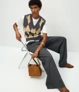 Pantalón de corte amplio tipo pantalona, confeccionado en tejido con patrón de rayas diplomáticas. Presenta cintura alta con trabillas para cinturón y cierre frontal tradicional.