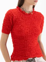 Top Charlotte de algodón y lino color negro, con calce al cuerpo, largo a la primera cadera, frunces en el exterior y escote semi alto con volado, al igual que los puños de las mangas cortas.