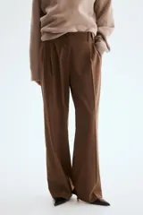 Pantalón de corte holgado color marrón, de estilo sastrero, con cintura clásica, trabillas para cinto y cierre con botón y cremallera. Presenta piernas rectas con pinzas frontales y bolsillos laterales.