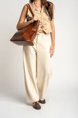 Chaleco de algodón color beige con estampado geométrico en tonos bordó y marrón. Presenta escote en V, cierre frontal con botones y corte recto.