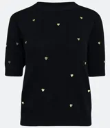 Blusa de punto negra con escote redondo, manga corta y apliques de corazones dorados.