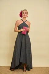 Vestido largo asimétrico color negro con estampado de lunares blancos, escote halter cruzado al frente y diseño con espalda descubierta.