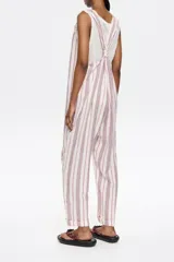 Mono largo de corte recto confeccionado en lino, con escote redondeado y tirantes con detalle de nudo ajustable. Presenta diseño de espalda nadadora y dobladillo en las piernas.