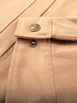 Campera color beige de gabardina 100% algodón, con cuello marrón de pana, cierre metálico reforzado, bolsillos internos y externos, forro de paño, puños y cintura ajustables.