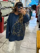 Buzo de punto color azul, con diseño de sol bordado en el frente, cuello redondo y corte holgado.