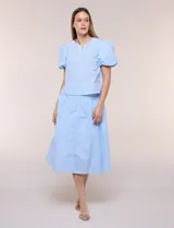 Blusa celeste a rayas blancas de calce recto con textura gofrada, cuello redondo con escote en V y mangas cortas abullonadas con elástico en los puños.