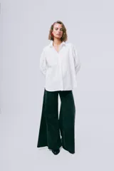 Camisa blanca de manga larga con cuello camisero, cierre frontal con botones y puños anchos.