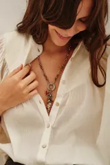 Collar de cadena dorada con dije circular y múltiples charms colgantes: corazón rojo, bota negra, trébol verde y bastón de caramelo con detalles de pedrería.