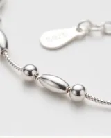 Pulsera de plata fina con abalorios de cuentas esféricas y cilíndricas intercaladas a lo largo de la cadena.