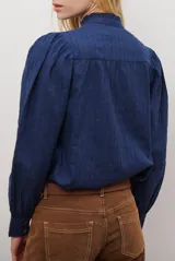 Camisa blanca de manga corta con cuello mao y volados, botones frontales y bordados de hojas y flores en color dorado.