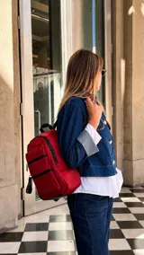 Mochila de tafeta color bordó, con compartimento principal con cierre, bolsillo frontal con doble cierre metálico y correas regulables.