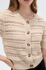 Saco de punto calado color camel, con cuello redondo, manga corta y cierre frontal con botones carey.