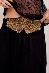 Cinturón negro con apliques decorativos dorados de lentejuelas y bordados en forma de abanico.