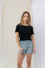 Short de jean azul claro con ruedo doblado fijo, tiro medio, calce cómodo, bolsillos delanteros y traseros, y cierre frontal con botón y cierre.