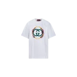 Remera Gucci blanca de manga corta, con cuello redondo y estampado gráfico frontal con el logo de la marca entrelazado y detalles ornamentales en dorado, verde y rojo.