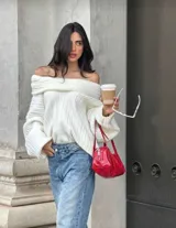 Buzo tejido de punto color crudo con diseño off-shoulder, textura acanalada y calce relajado.