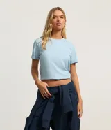 Remera básica de cuello redondo y manga corta con detalle de dobladillo, confeccionada en algodón suave.