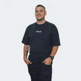 Remera de corte oversize, color negro con efecto acid wash, cuello redondo y manga corta. Presenta un pequeño texto bordado en el pecho que dice "RELAJO".