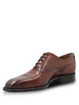 Zapato de vestir tipo Oxford en cuero color marrón, con puntera reforzada y cierre mediante cordones. Presenta un diseño clásico con suela mixta de cuero y goma.
