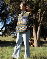 Buzo polar de cuello alto con cierre frontal de botones a presión, confeccionado en tejido fleece sintético con estampado geométrico multicolor. Presenta un bolsillo frontal con solapa y cierre de botón, además de bolsillos laterales ocultos.