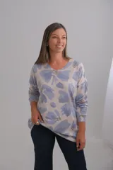 Sweter de punto amplio con escote en V y manga larga. Presenta un estampado floral estilo acuarela en tonos azul y gris sobre fondo claro.