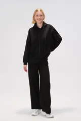 Canguro negro holgado con capucha y cordones ajustables, mangas largas y bolsillos laterales.