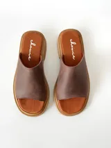 Sandalias de cuero color chocolate, con faja ancha en el empeine, plantilla de gamuza y suela plana con taco bajo.
