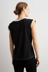 Remera sin mangas de corte recto, confeccionada en dos tonos, con frente en color beige claro con escote en V y espalda en color negro. Cuenta con detalle de botones en los laterales.