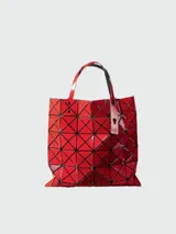 Bolso tote rojo con diseño geométrico de triángulos negros, doble asa superior y etiqueta colgante.