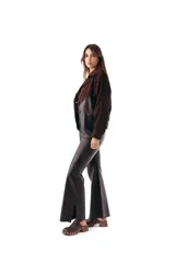 Campera bomber de cuero ovino negro combinada con gamuza chocolate, cuello solapa y cierre frontal de botones. Presenta mangas largas con detalles de costuras decorativas y bolsillos laterales ribeteados.