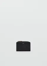 Billetera pequeña de diseño compacto en color negro, con textura granulada y cierre metálico dorado. Presenta el logo de la marca grabado en la parte frontal.