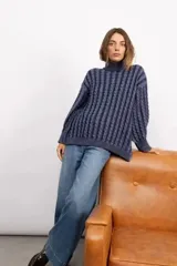 Sweater de tejido de punto con diseño de trenzas verticales, cuello alto, manga larga y silueta oversize de largo extendido.