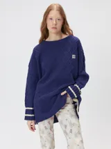 Sweater de punto con diseño de rombos en relieve, cuello redondo y calce holgado. Presenta aberturas laterales en el ruedo y logo bordado en el pecho.