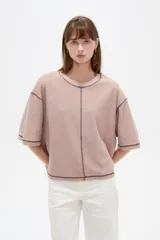 Remera de algodón color crudo, con cuello redondo a la base, mangas 3/4 holgadas y costuras con pespuntes en tono contrastante.