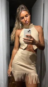 Top polera beige de cuero sintético con cuello alto, corte halter y abertura en el abdomen.