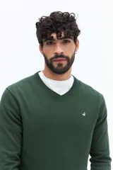 Sweater de punto color gris melange, con escote en V, manga larga y logo bordado en el pecho. Presenta puños y ruedo acanalados.