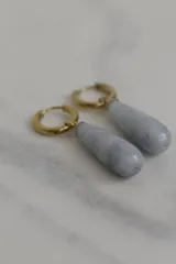 Aros tipo argolla con dije colgante en forma de gota de piedra natural en tonos marrones. Fabricados en acero quirúrgico dorado.