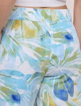Pantalón crop de lino y rayón, con diseño wide leg de corte holgado, estampado tropical de hojas en tonos verde, azul y marrón sobre fondo blanco. Cuenta con pretina trasera elastizada y bolsillos delanteros.